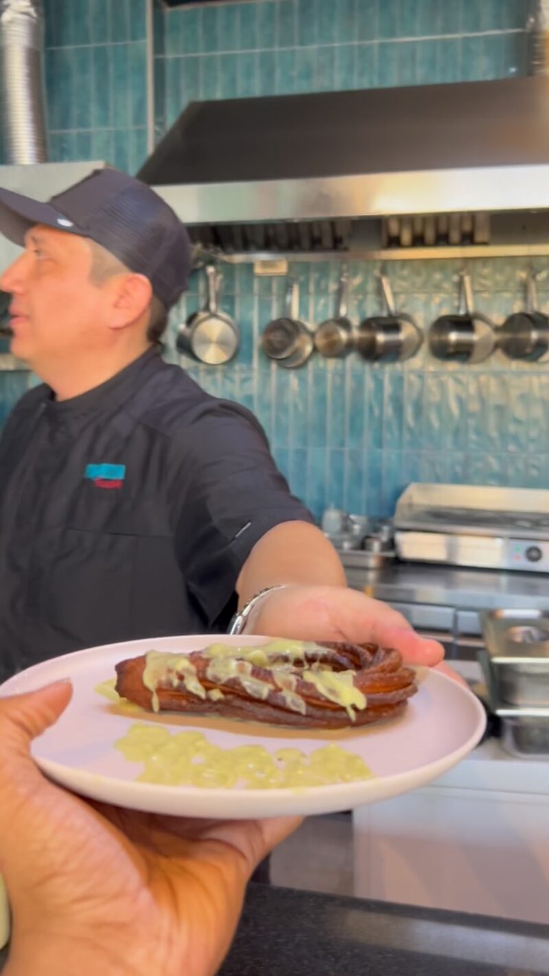 The chef at the flat top in the teal-tiled open kitchen