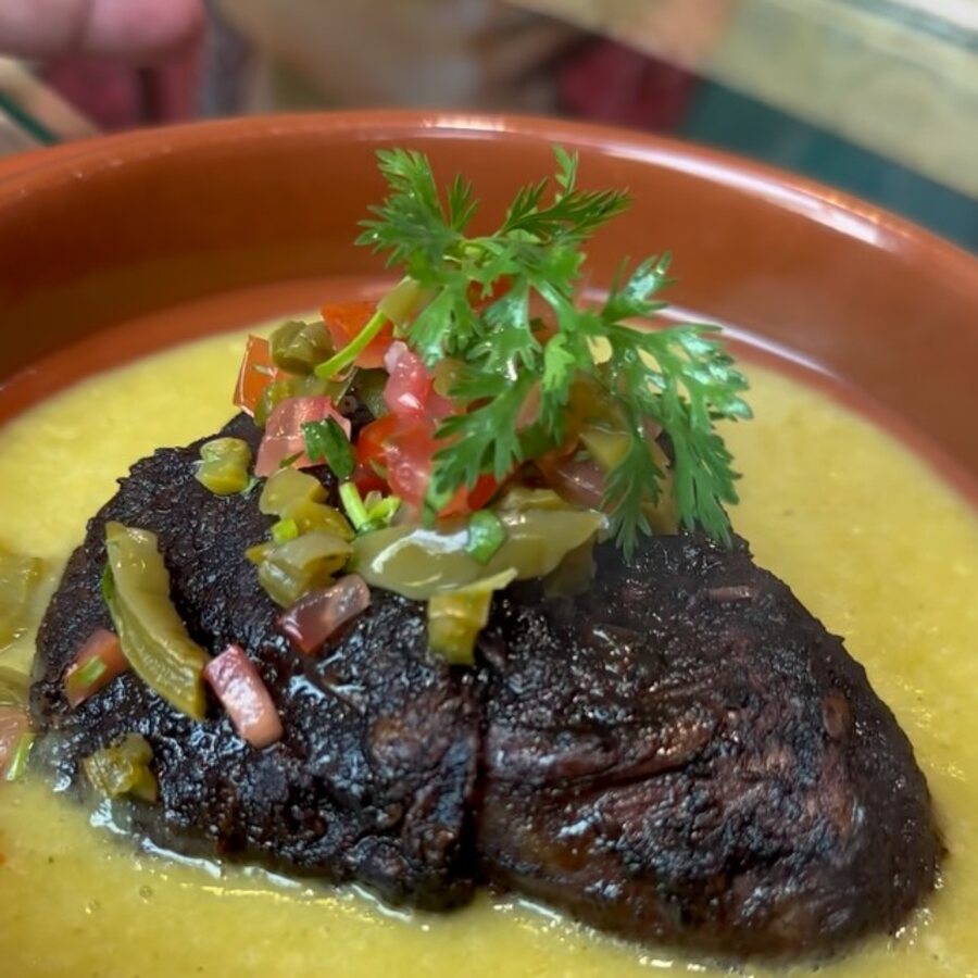 Slow-cooked beef cheeks over tomatillo salsa in a terracotta dish